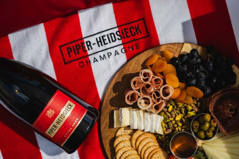 Piper Heidsieck champagne bottle with charcuterie board and red striped napkin