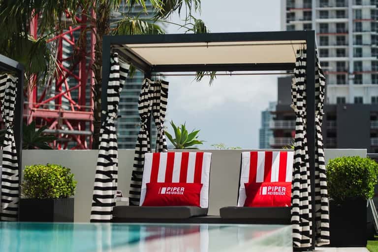 Modern black pergola with striped cabanas and pool reflection in foreground