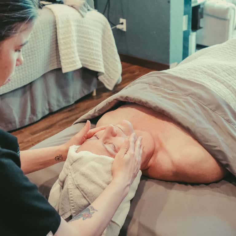 Newborn baby wrapped in white cloth being held by caregiver's hands in hospital room