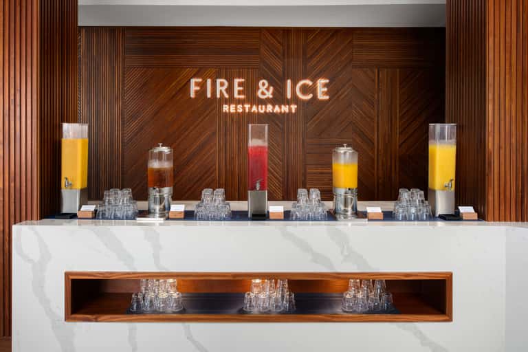 Fire & Ice Restaurant reception desk with elegant marble counter, neon signage, and beverage dispensers