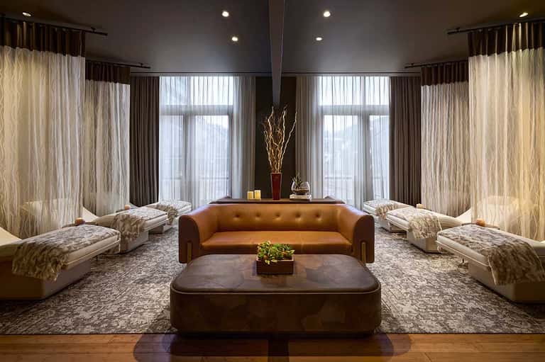 Luxury lounge with brown leather sofa, cream seating, floor-to-ceiling windows, dark ceiling, and modern decor