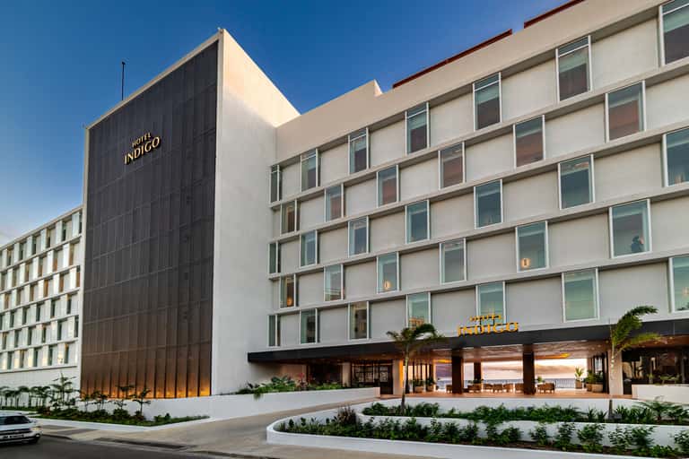 Modern Hotel Indigo exterior with contemporary architecture, white and dark facade, palm trees, daytime