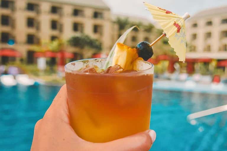 Tropical cocktail with pineapple and umbrella garnish by poolside