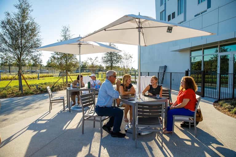 Outdoor patio with guests dining under umbrellas overlooking green landscape