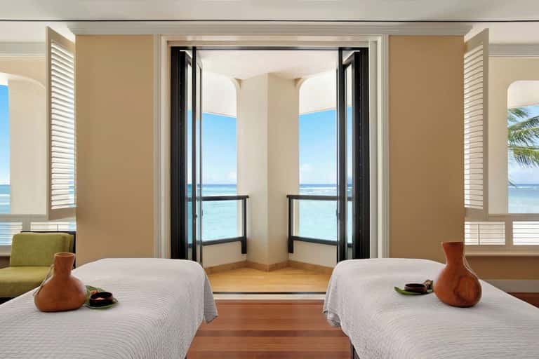 Dual massage bed spa suite with ocean balcony access and turquoise water views