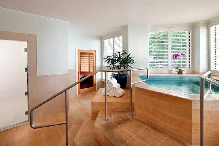 Spa facility featuring indoor pool with mosaic tiles and wooden railings