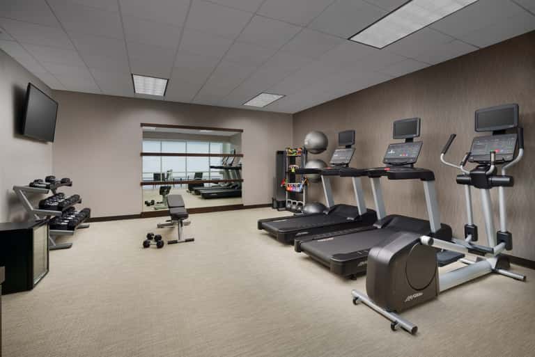 Fitness center with treadmills, exercise bikes, dumbbells, and wall-mounted TVs