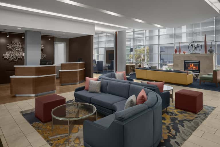 Hotel lobby lounge with curved seating, fireplace, reception desk, and modern decor