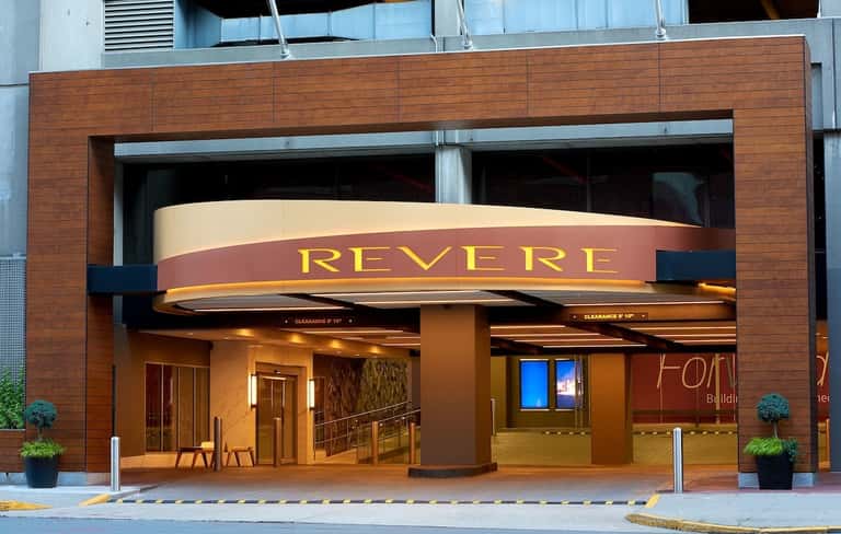 Revere hotel entrance with modern curved signage, brick facade, and welcoming ground-level entry