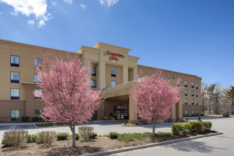 Hampton Inn exterior with blooming pink cherry blossom trees and main entrance with traditional signage