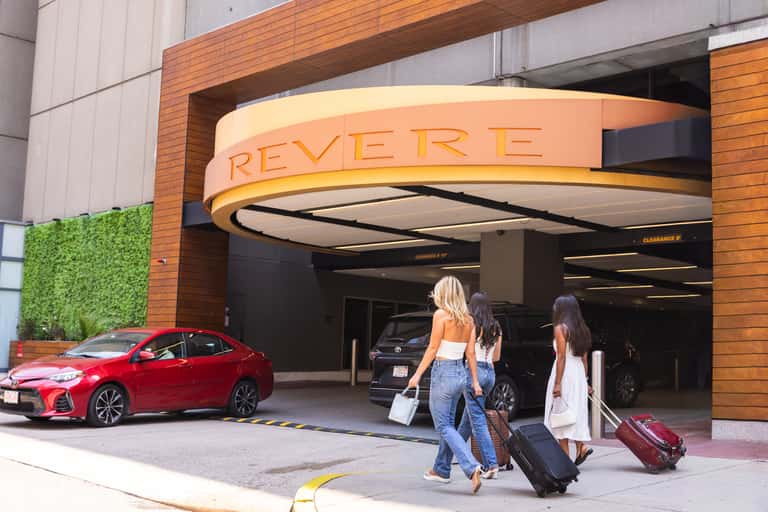 Revere hotel entrance with porte-cochere and guests with luggage arriving by car