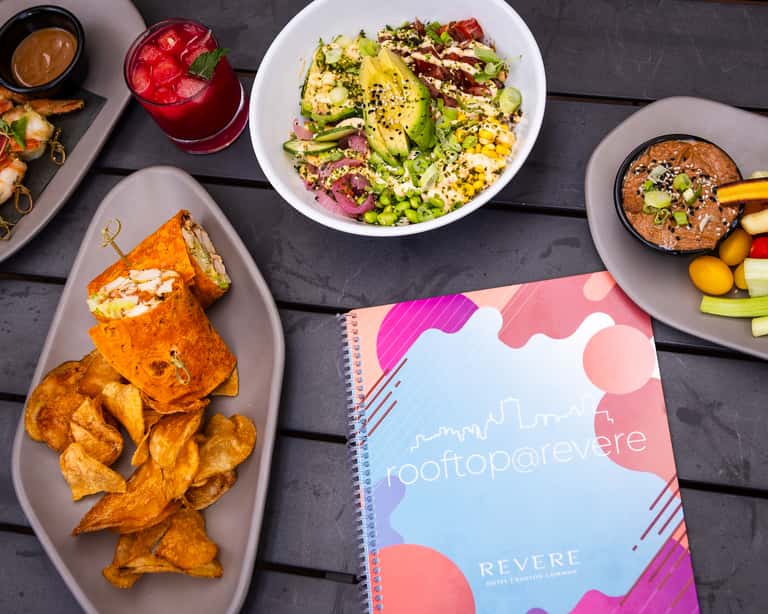 Colorful appetizers and cocktails on dark table with Revere branding and vibrant presentation