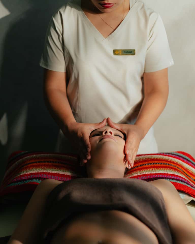 Spa therapist performing a facial massage on a client on a treatment table