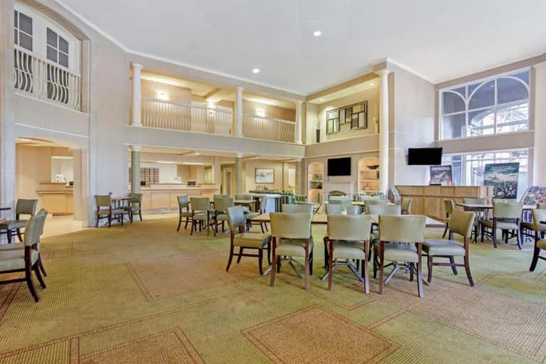 Spacious hotel lobby with two-story atrium, seating areas, front desk, and large windows