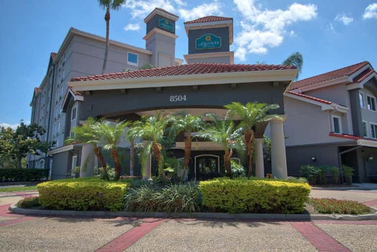 La Quinta hotel entrance during daytime with covered portico, palm trees, and manicured grounds