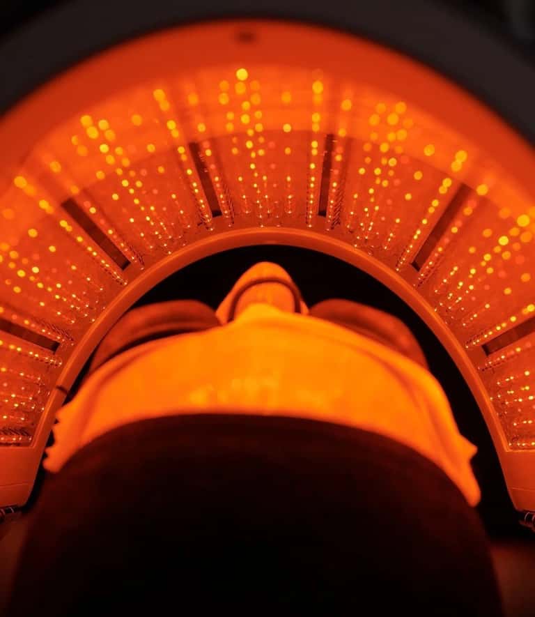 Red neon tanning bed canopy glowing brightly with illuminated detail inside the bed chamber