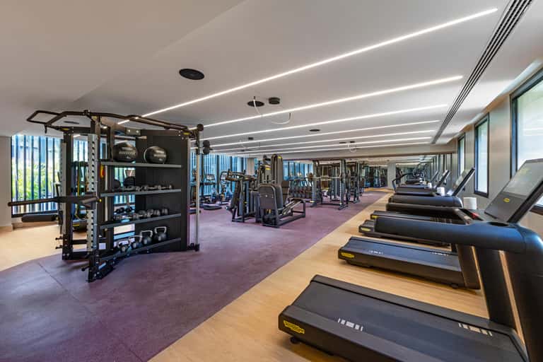 State-of-the-art fitness center with treadmills, exercise equipment, linear ceiling lights, and city views through windows