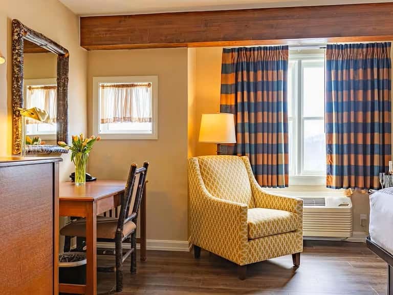Upscale hotel room with queen bed, striped drapes, wood desk, and comfortable seating area