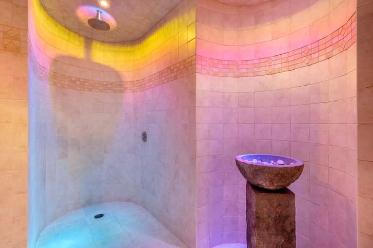 Chromotherapy steam room with colorful LED lighting and stone bath fixture