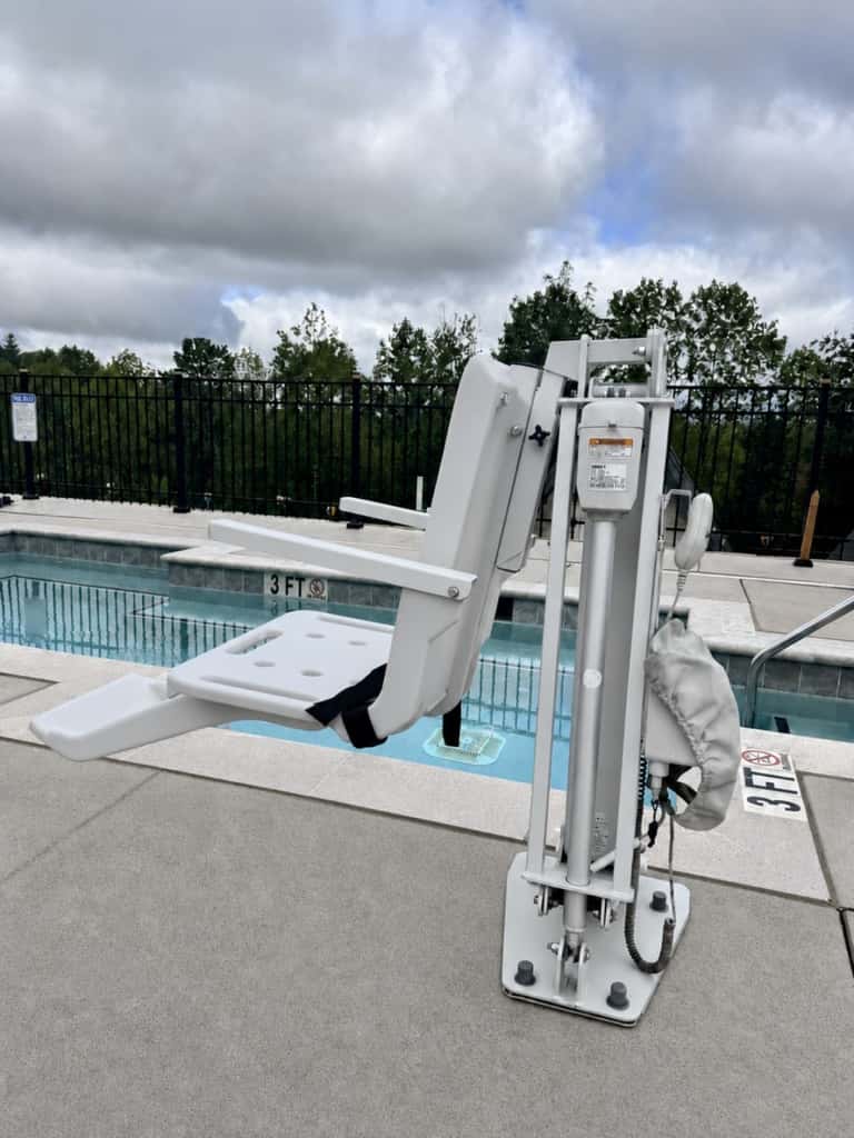 Accessible pool lift device at edge of indoor pool facility