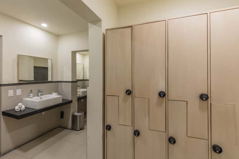 Spa locker room with wooden lockers, white sink counter, and rolled towels in neutral tones