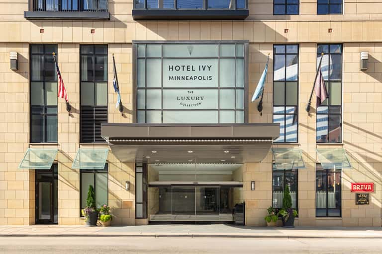 Hotel Ivy Minneapolis entrance facade with stone exterior, glass doors, awning, and luxury collection signage