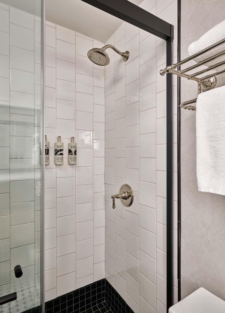 Modern shower stall with white subway tiles, rainfall showerhead, and brushed nickel fixtures in a luxury bathroom