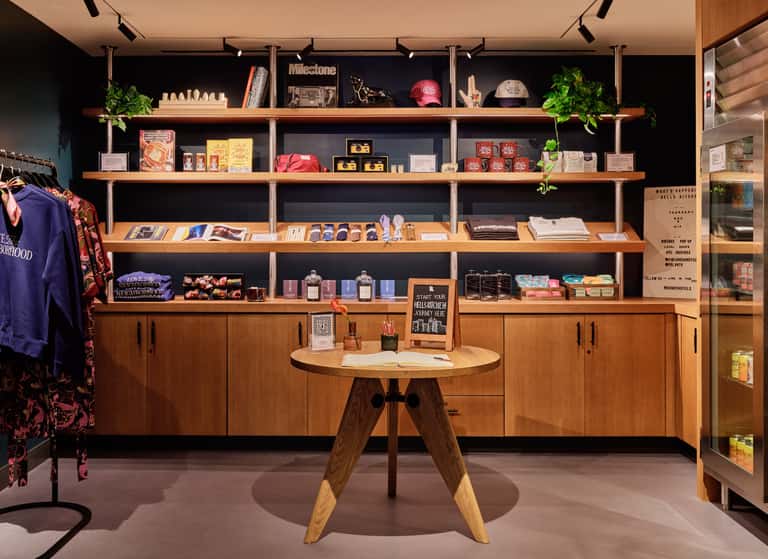 Contemporary retail shop with wooden shelving, curated merchandise displays, and round wooden tasting table