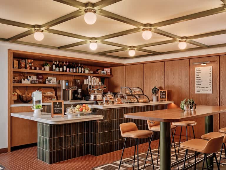 Mid-century modern cafe with wood paneling, brass ceiling fixtures, and cognac leather bar seating