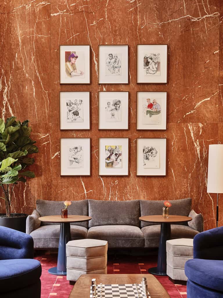 Sophisticated lounge with rust marble wall, framed art collection, gray sofa, and blue accent chairs