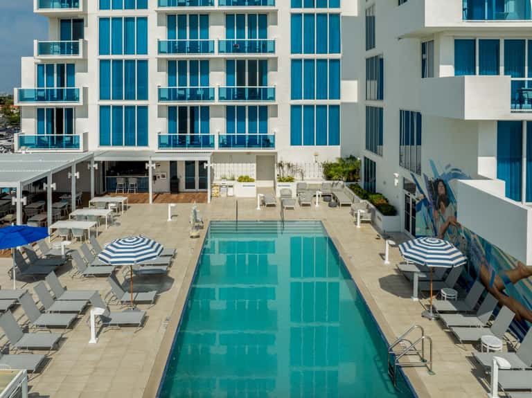 Contemporary hotel courtyard with turquoise lap pool and white modern architecture