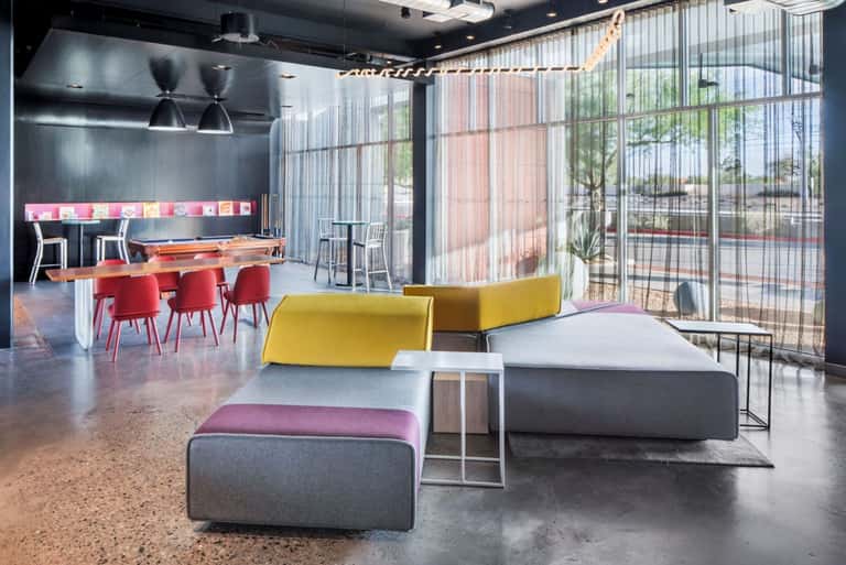Modern hotel lounge with colorful modular seating, pool table, and floor-to-ceiling windows