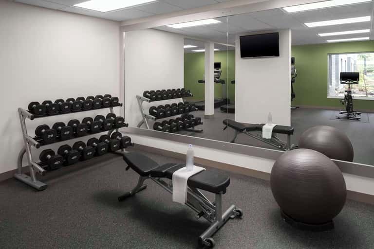 Fitness center with dumbbell racks, exercise bikes, stability balls, and wall-mounted TV