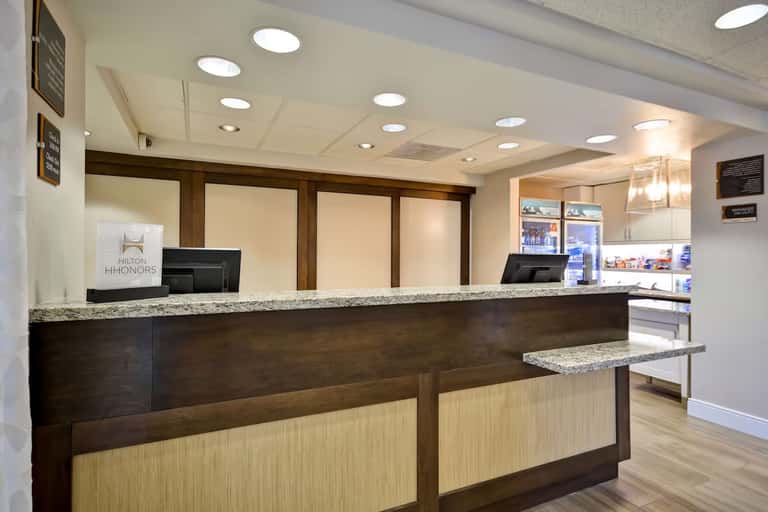 Hotel front desk with dark wood cabinetry, granite countertop, and Hilton HHonors signage