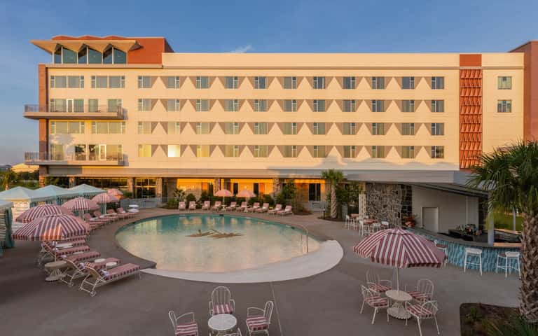 Mid-century resort with geometric patterned facade, pink umbrellas, and kidney-shaped pool