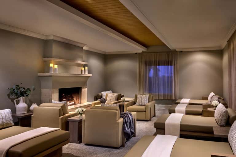 Luxurious spa lounge with fireplace, neutral seating, ambient lighting, and elegant décor