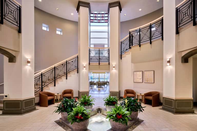 Modern multi-story hotel atrium with spiral staircase, geometric railings, and plants
