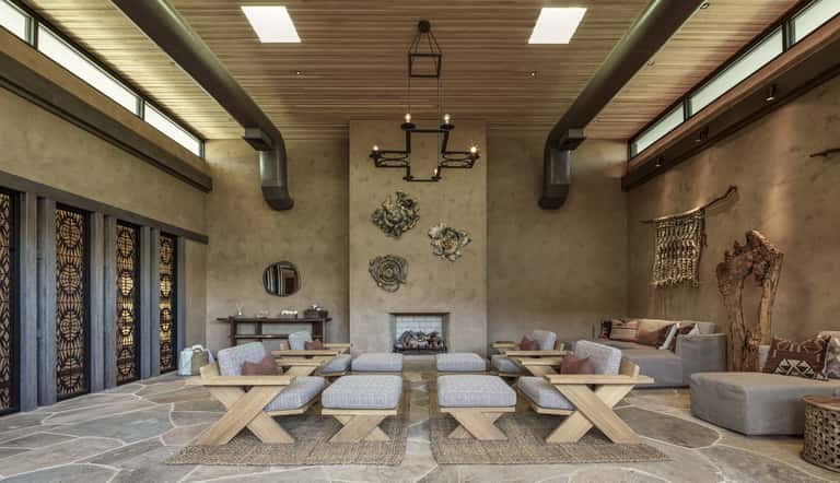 Modern spa lounge with fireplace, geometric furniture, decorative wall art, and high wood ceiling