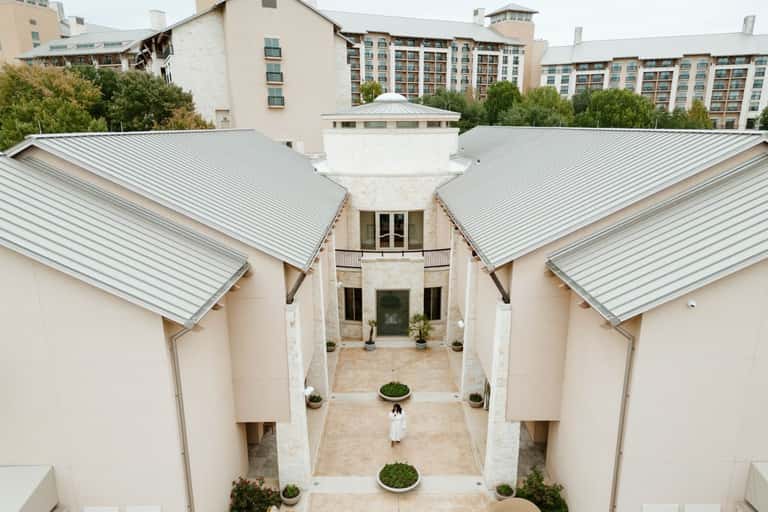 Modern spa courtyard with symmetrical white buildings, metal roofing, and minimalist landscaping