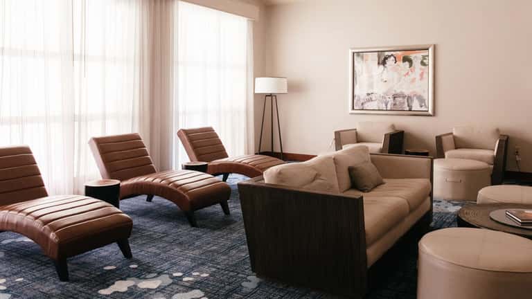 Upscale hotel lounge with curved seating, leather chaise lounges, floor-to-ceiling windows, and contemporary artwork