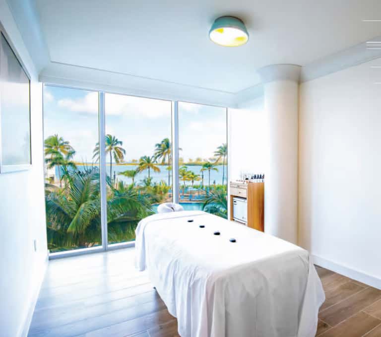 Massage treatment room with ocean and lagoon views through floor-to-ceiling windows