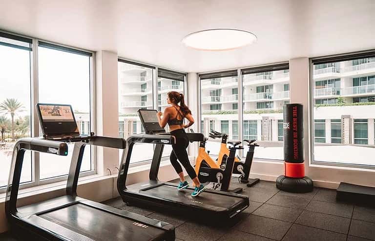 Modern fitness center with treadmills, stationary bikes, and floor-to-ceiling windows