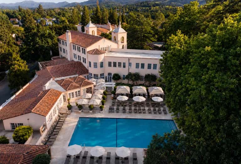 Luxurious resort courtyard with swimming pool, white umbrellas, and Mediterranean architecture