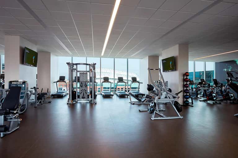 Bright fitness facility with various exercise machines and equipment with large windows and city views