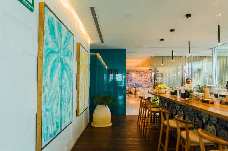 Upscale restaurant interior with turquoise artwork, wooden counter seating, and warm ambient lighting