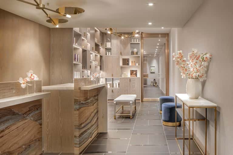 Luxury spa reception area with wooden cabinetry, marble counters, flowers, and minimalist design