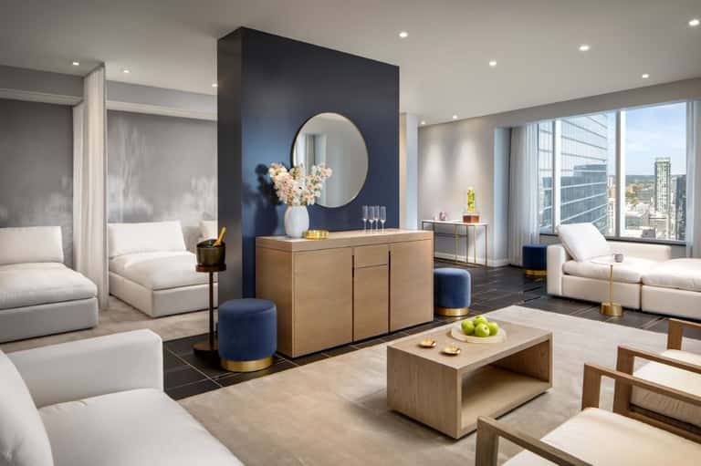High-rise hotel suite with navy accent wall, multiple seating areas, marble fireplace, and city views