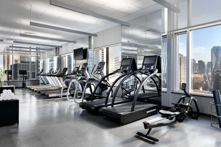 Modern high-rise gym with cardio machines, treadmills, exercise bikes, and panoramic city skyline views