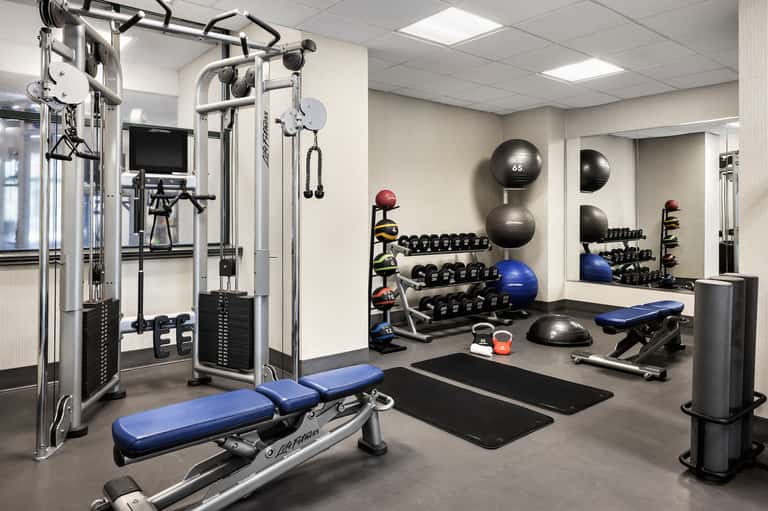 Fitness center with weight equipment, dumbbells, exercise machines, and stability balls on dark flooring
