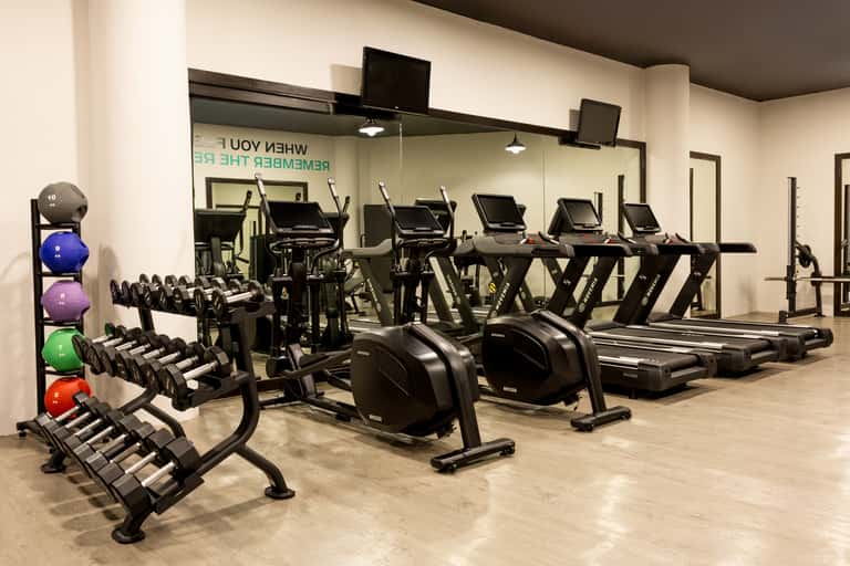 Fitness facility with dumbbell rack, cardio machines, exercise bikes, and mirrored walls